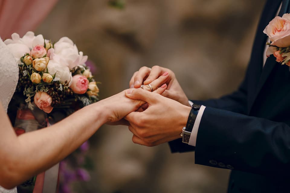 A man and woman holding hands in front of flowers.