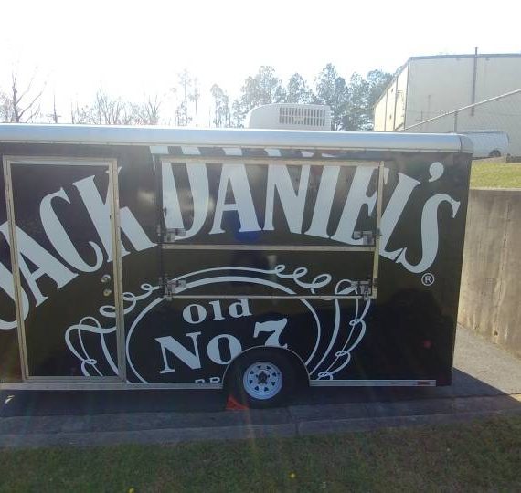 A jack daniels trailer is parked on the side of the road.
