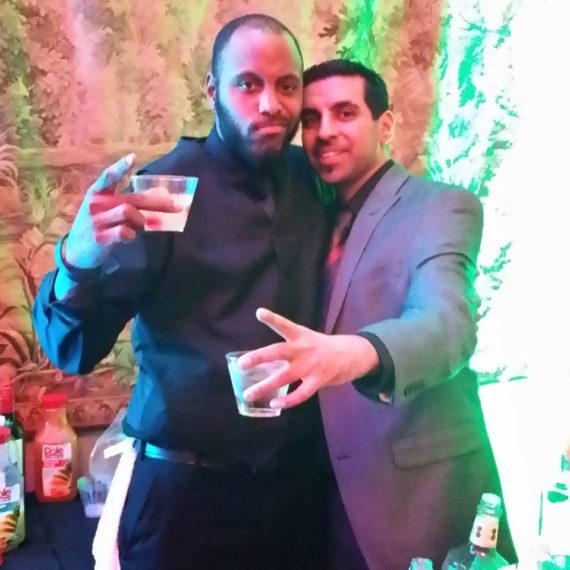 Two men pose for a picture while holding drinks.