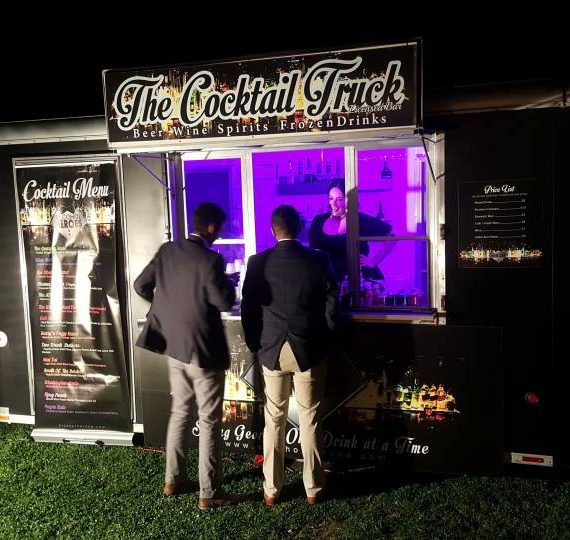 Two men standing in front of a cocktail truck.