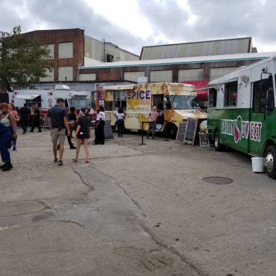 A group of people standing around food trucks.