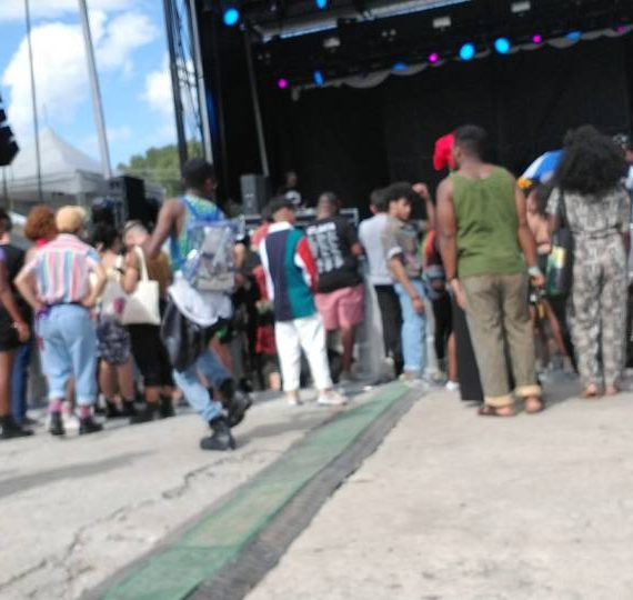 A group of people standing around in front of an outdoor stage.