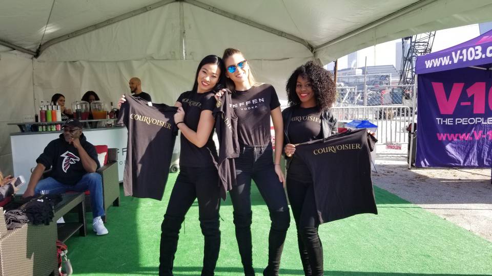 Three women in black shirts and one woman holding a shirt.