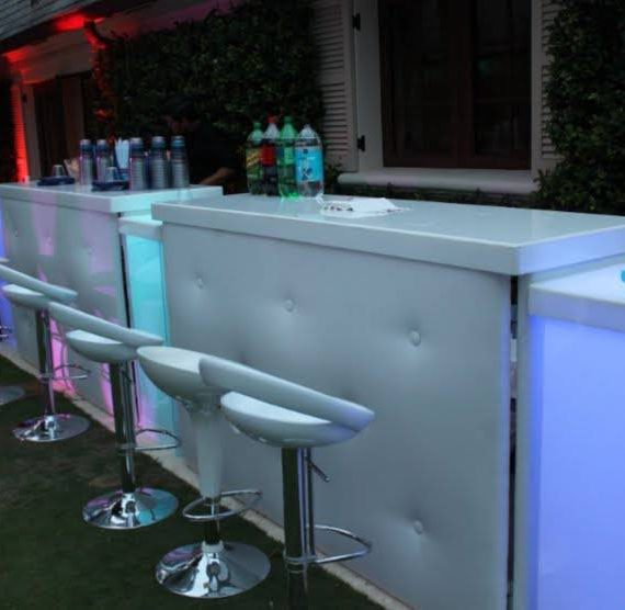 A bar with white stools and blue lights
