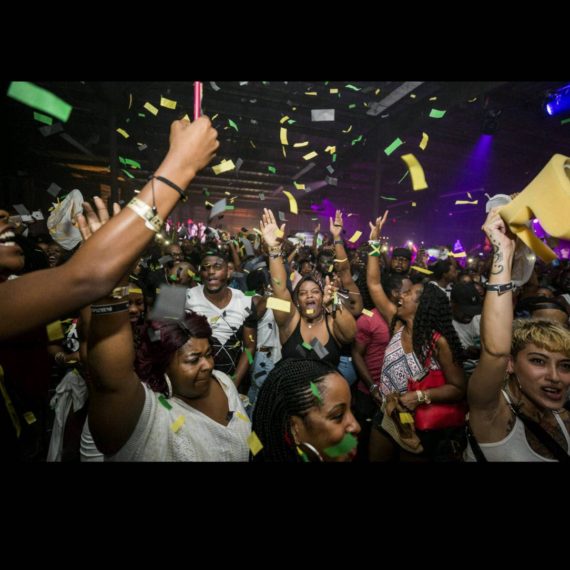 A crowd of people in a room with confetti falling.